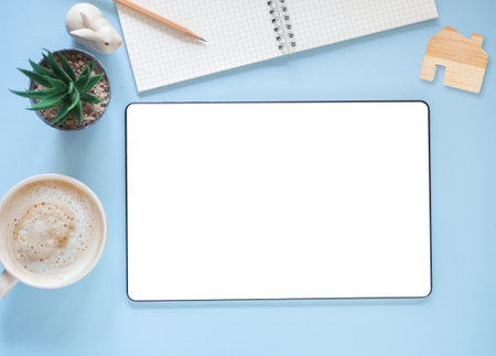 Blank screen of tablet and coffee cup, cactus, nooteboo on blue workplace. Top view, flat lay with copy space. Template for business and education.の写真素材
