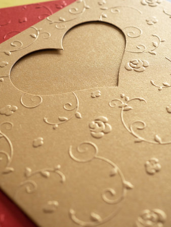 Gold greeting card pierced into a heart shape and pattern a small flower shape over red paper. The concept for image, text, design.の写真素材