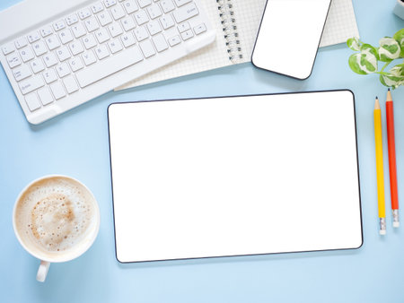 Top view, flat lay template, mock-up digital tablet pc computer with blank white screen and coffee cup, smartphone, keyboard, pencil on blue workplace.Business, technology concept.の写真素材