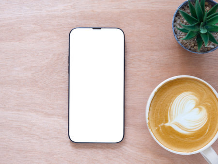 Top view, flat lay with copy space. Smartphone mockup screen on wooden office table, coffee cup and...