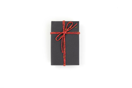 Top view, black gift box tied with a bow isolated on white background. Gift box concept for a happy birthday, thank you, congratulation, mother's day, anniversary, Valentine's Day, or other holidaysの写真素材