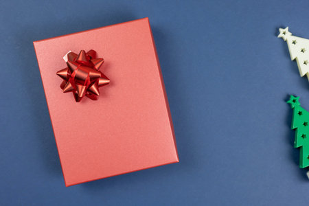 Red gift box with red bow on a dark blue background. Top view, flat lay with copy space. Concept for...