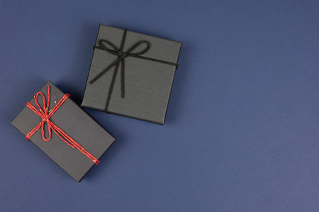Gift box concept for happy birthday, thank you, congratulation, mother's day, anniversary, and holiday. Top view with copy space of black gift box on dark blue background.の写真素材