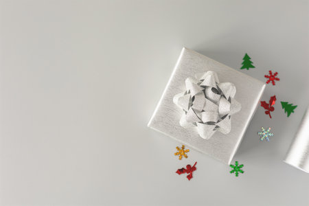 Top view, silver gift box with silver bow on grey background and gift wrapping paper, confetti. Flat lay with copy space. Concept for holiday.の写真素材