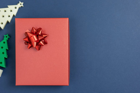 Red gift box with red bow on a dark blue background. Top view, flat lay with copy space. Concept for...