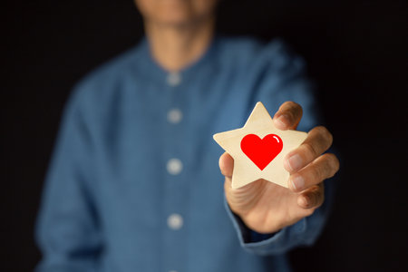 Concept of positive emotions. A man holds a star shape and a red heart inside. Positive thinking, Satisfaction Rating and reviews, recommendations.の写真素材