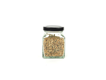 Peeled sunflower seeds in a square glass bottle with black lid isolated on a white background.の写真素材