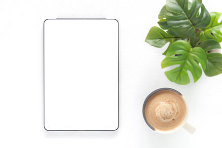 Top view of a digital tablet with a blank white screen and coffee cup over a white wooden background. Mockup, template for business. Concept online shopping, blog, logo, product, and social media.の写真素材