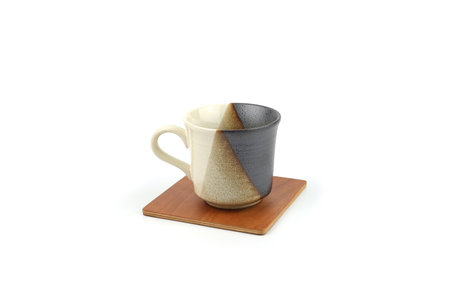 Two-tone ceramic coffee mug on a wooden coaster, isolated on a white background.Template for food design, and banner. Use for home or restaurant, ideal for cozy beverage.の写真素材