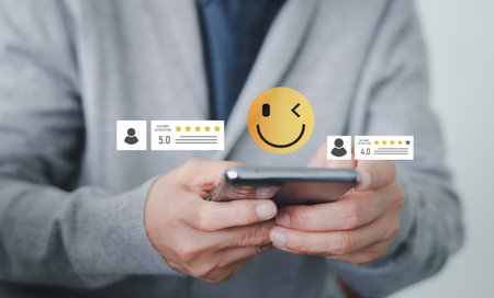 A person is holding a smartphone and giving a positive review, with a smiley face emoji and high rating icons appearing phone. Customer satisfaction, online feedback and marketing digital business.の写真素材