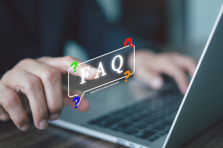 Businessman using a laptop to search for information in an FAQ. A virtual pop-up shows 'Frequently Asked Questions', representing a concept of customer support, online helpdesk. Ask and consulting.の写真素材