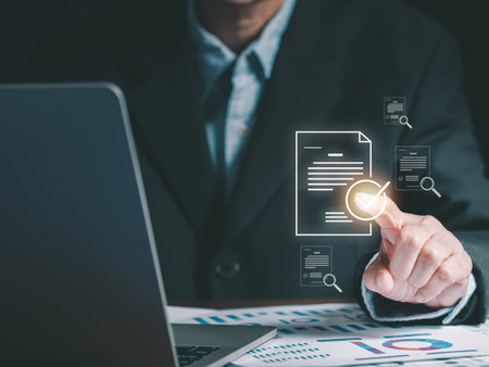 A businessman is pointing to a digital overlay of a document with a checkmark, symbolizing the concepts of document verification, approval process, and digital security. Paperless office solutions.の写真素材