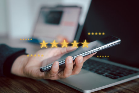 A person is holding a smartphone, with a digital overlay of five golden stars floating above it. Concept of online customer satisfaction, positive reviews, service quality, and product excellence.の写真素材