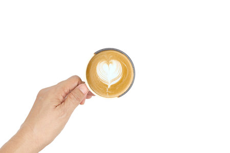 A high-angle close-up of a barista's hand holding a white porcelain cup of hot latte coffee with a beautiful heart-shaped foam art on the top,  isolated on a white background.の写真素材