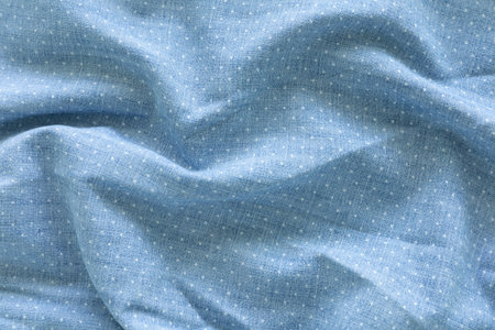 Top view, close-up shot of a light blue fabric with a subtle, evenly distributed white polka dot...