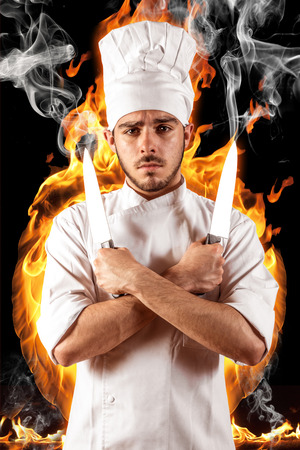 Young chef with knife and fire and smokeの写真素材