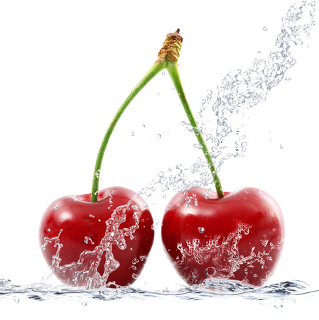 fresh cherries falling in waterの写真素材