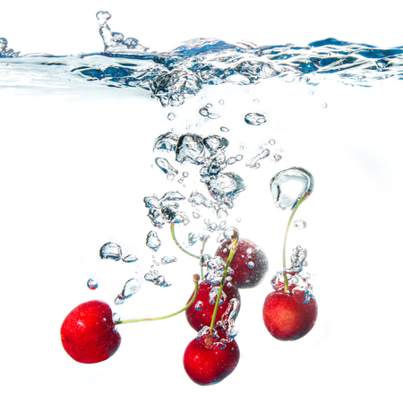 fresh cherries falling in waterの写真素材