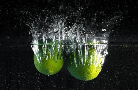 fresh lime falling in waterの写真素材