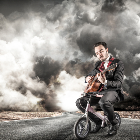 young manager play a classic guitar on a little bikeの写真素材