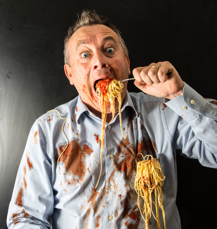mad man eating spaghetti with tomato sauceの写真素材