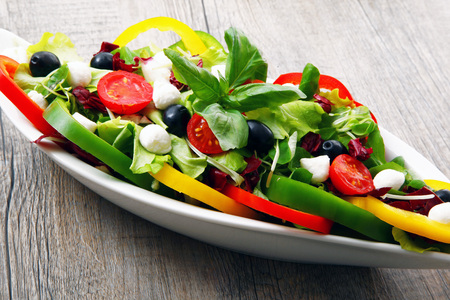 salad with tomatoes,olive peppers and cheese on old wooden tableの写真素材