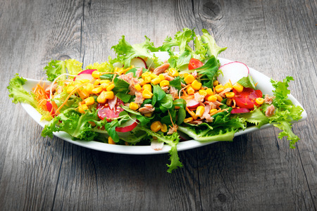 salad with tomatoes and mais on old wooden tableの写真素材