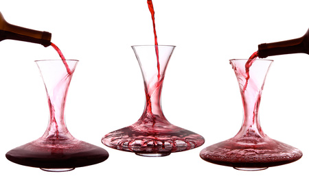 Red wine poured into decanter on white backgroundの写真素材