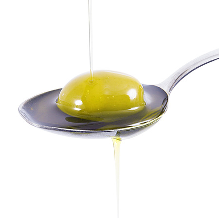 olive oil on spoon on white backgroundの写真素材