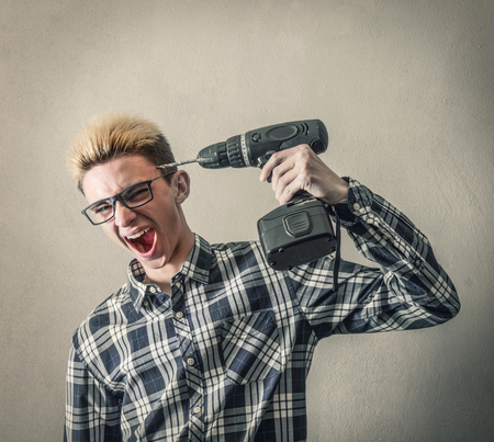 a Boy points a drill in the headの写真素材