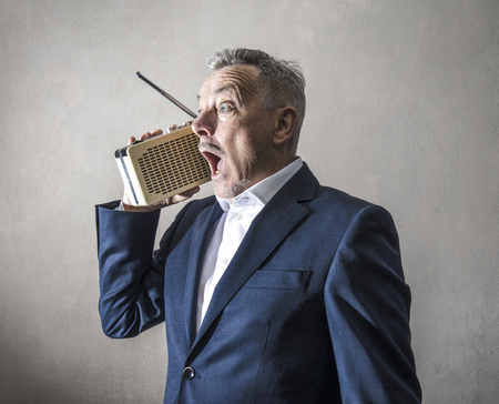a Businessman listening to the radio making strange expressions