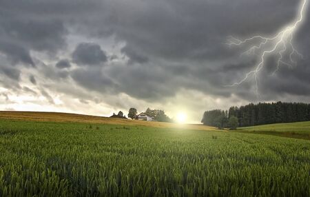 farmhouse with a thunder-storm and sunの写真素材