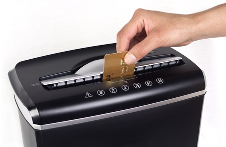 Female hand cutting or shredding a gold credit card with a black shredder isolated with copy space on white background の写真素材