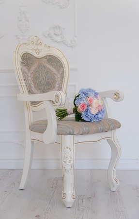 A white antique chair with a blue flower bouqet lying on it