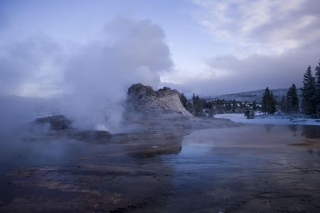 Evening shot of Castle Geyser with the moon behind the stream vent の写真素材