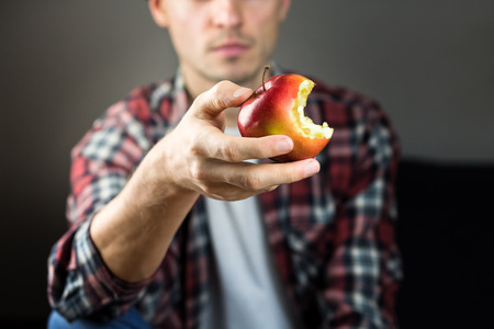 Young male person with red bitten apple in handの写真素材