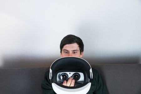 Man going to use VR headset. Male person holding and looking at virtual reality glasses at home