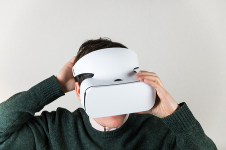 Man portrait in virtual reality headset. Male person wearing vr box adjusts it comfortable on his...