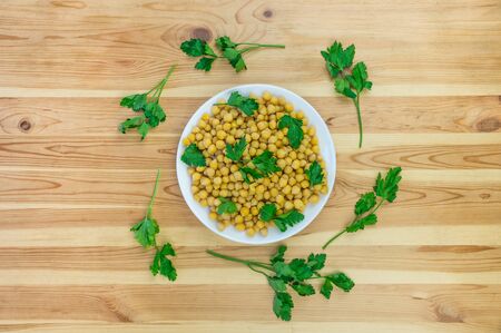 Cheakpea and parsley top view. Bowl of cooked gram-chick peas seasoned with parsley as flat lay on wood tableの写真素材