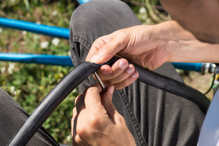close up image of person using glue to repair inner tube of bicycle wheel on the roadの写真素材