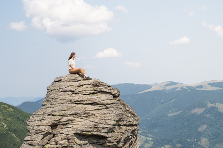 person in casual clothing poses on a cliff and looks into far away distanceの写真素材