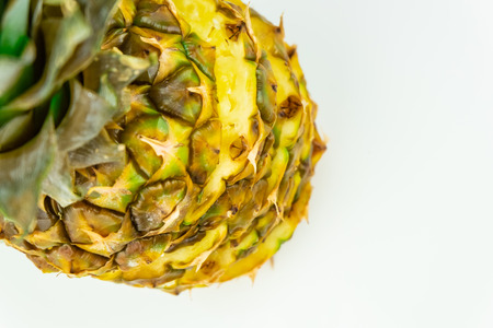 One sliced pineapple on isolated white background, shot from above. Top view of ripe fresh pineapple standing on white tableの写真素材