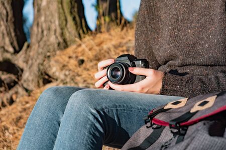 Vintage film camera in female hands. Close up shot of a woman holding film camera outdoorsの写真素材