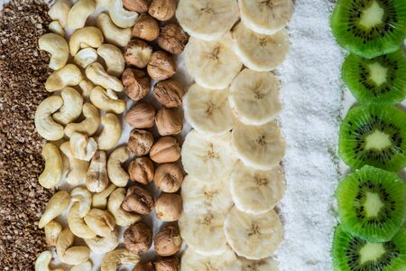 Fresh ingredients for a healthy raw food breakfast. Kiwi, coconut flakes, cashews and hazelnuts shot...