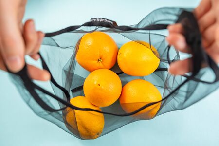 Top view of oranges in a reusable string bag. Sustainable eco packaging concept: shopping for groceries with a multi-use bag to reduce ecological footprintの写真素材