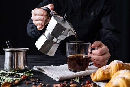 Pouring coffee from an italian percolator, shot in low key. Male hands pour black coffee from italian moka brewerの写真素材