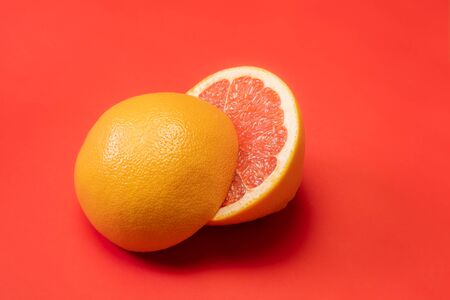 Grapefruit cut in half on vivid red background, copy space. Fruitarianism, vegetarian or vegan food:...