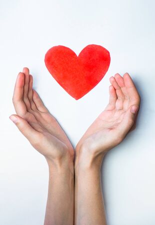 Heart sign drawn with a marker pen and hands embracing it. Concept of love, care and peace: shape of a heart resting safely in human palms.の写真素材