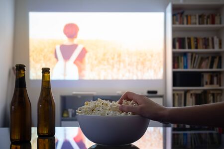 Home cinema entertainment: watching a film from a video projector in a room. Dim living room with a...