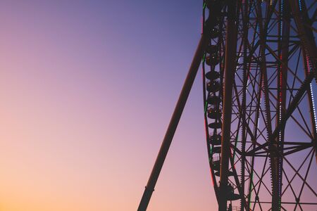 Observation wheel silhouette in bright evening sky. Fairground ride and beautiful evening sky, bright and vivid moody colors.の写真素材